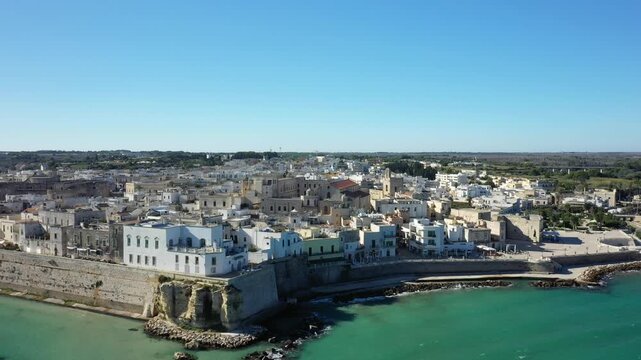 Scenic aerial view of Otranto, Italy, showcasing the historic architecture and turquoise coastline under a clear blue sky.
