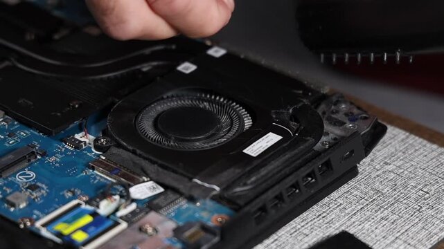 Laptop fan repair and internal cleaning process with screwdriver to restore cooling system and prevent overheating close up technical maintenance concept