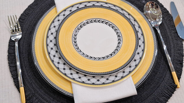 Top view of luxury ceramic plate set with elegant patterns and professional cutlery arrangement for fine dining table setting