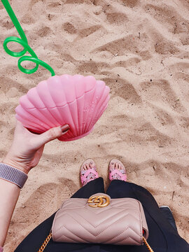 Lifestyle of luxury Gucci quilted leather handbag and pink seashell cocktail drink on tropical sand beach background for illustrative editorial use on February 16, 2022in chonburi, Thailand