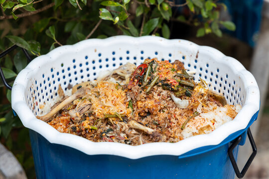 Close-up of leftover food waste in a plastic bin, showing rice, bones, vegetables and spicy mixed ingredients. Concept of food waste problem, household garbage, environmental pollution, composting and