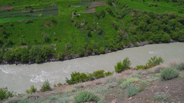 River Chenab flowing between the Himalayan mountain valley as seen from Udaipur village in Lahaul, Himachal Pradesh, India during the summer season. River flows in between the mountain valley.