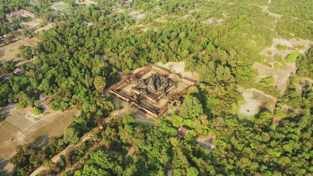 Drone shot of the ancient Banteay Samre temple surrounded by lush green forest in Cambodia. The historic structure stands out amidst the natural landscape.