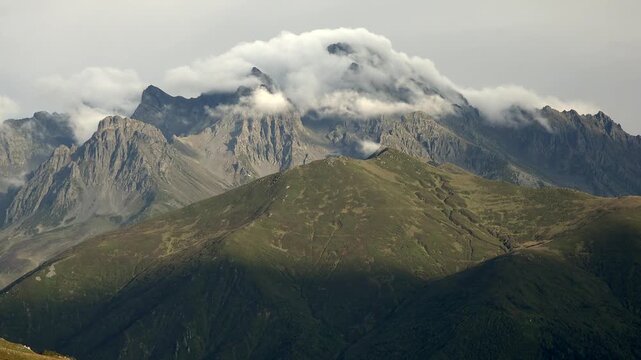 Rocky Mountains fog timelapse over rugged peaks as clouds spill across alpine ridges. USA range crests in haze, swift vapor streams around jagged summits during changing weather.