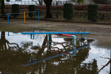 A seesaw over a puddle in a park after the rain