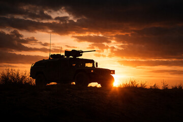 Fototapeta premium A military vehicle silhouetted against a dramatic sunset, evoking a sense of power and readiness. The scene showcases the vehicle's rugged design with a machine gun mounted on top.