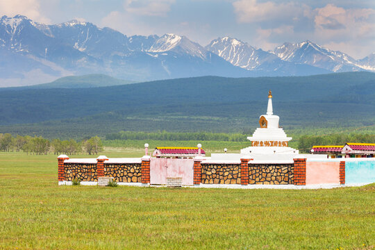 Buddhist Stupa of enlightenment on green spring meadow against the backdrop of the Eastern Sayan Mountains on a sunny day. Siberia, Buryatia, foothill Tunka Valley, Nature Park