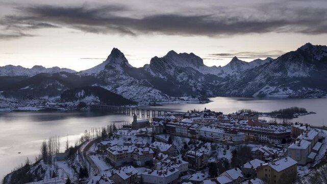 Snowy Village Sunset to Night Time Lapse. A high-angle time lapse of Riano village in the Leon mountains during winter. The footage shows the transition from sunset to night over the snowy landscape