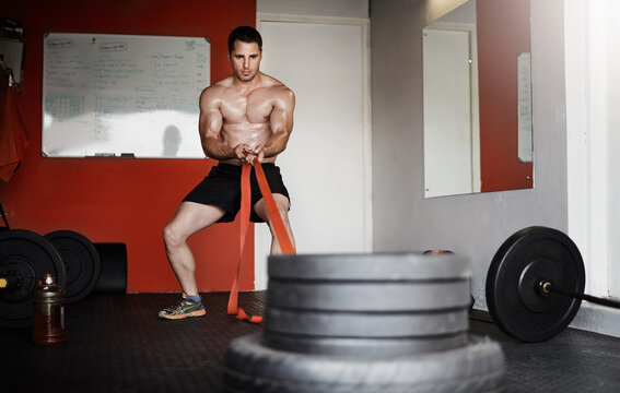 Exercise, heavy and weight training with man in gym for bodybuilding or performance. Drag pull, fitness and muscle power with shirtless bodybuilder in health club for challenge or workout routine