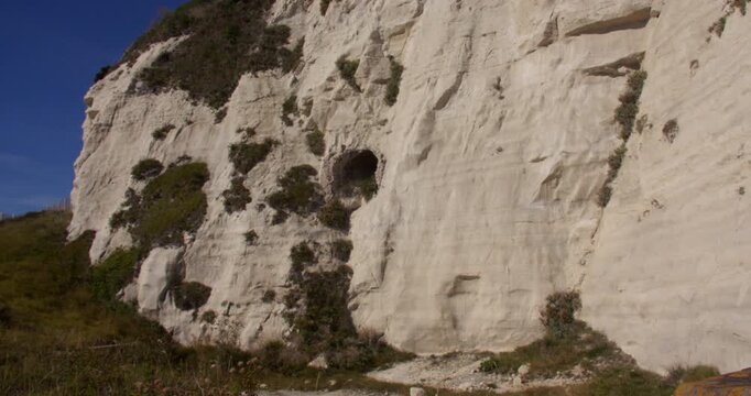 Extra wide shot of the white cliffs of Dover with a brick lined tunnel entrance in the side of the cliffs