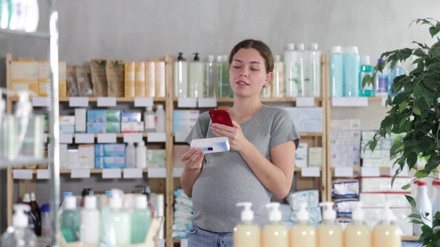 Attentive pregnant woman buyer scanning qr code for box of ointment or gel in small pharmacy