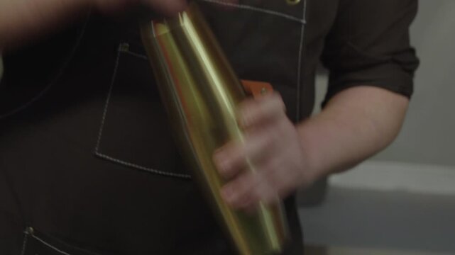 Barman pouring liquid from a shaker into a glass