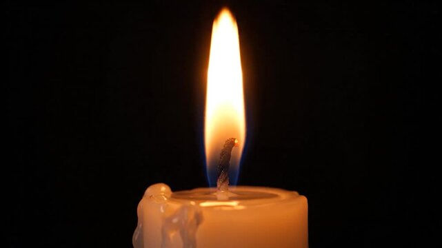 A match ignites a candle wick, creating a burst of bright sparks in the dark.