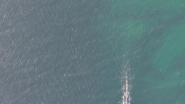 Aerial View of Small Outrigger Boat Moving Across Turquoise Ocean Waves