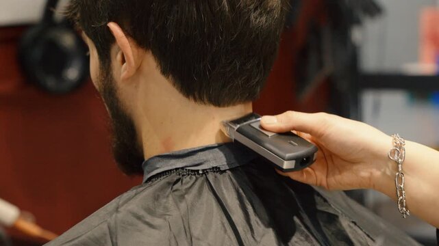 Stylist using electric hair clipper for male haircut