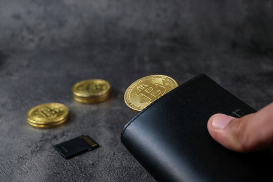 A wallet corner with multiple crypto coins and a microSD card on a dark surface