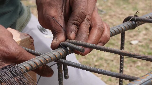 Construction worker fastening steel rebar together using a tying wire