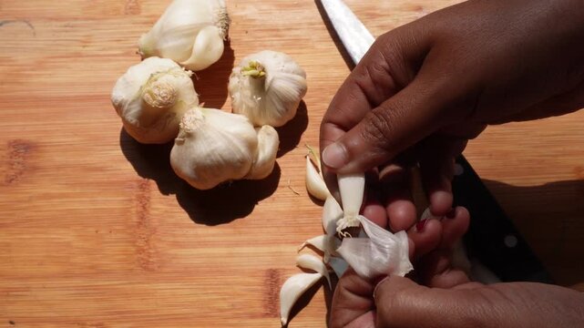 Preparing fresh garlic for cooking on a wooden surface