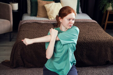 Young woman stretching in a cozy bedroom during morning routine for relaxation and flexibility