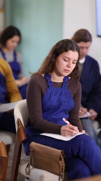 In lecture, girl employee writes on large piece of paper, fills out questionnaire, answers exam questions. Professional aptitude, identification of initiative and talented employees 