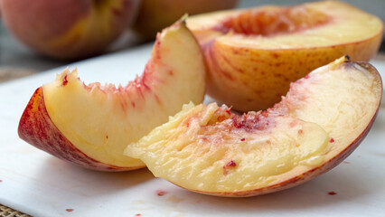Fresh peaches sliced on a white cutting board ready to eat during summer gatherings in a kitchen setting