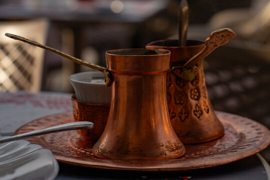 Bosnian coffee in traditional copper dzezva pot with fildzan cup and turkish delight close up.
