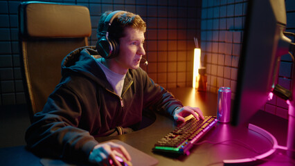 Young teen streamer gamer man playing online video game on computer. Esport concept gaming virtual entertainment. Cyber e sport videogame tournament live stream. Neon light. Tense player competition. © Татьяна Епанешникова