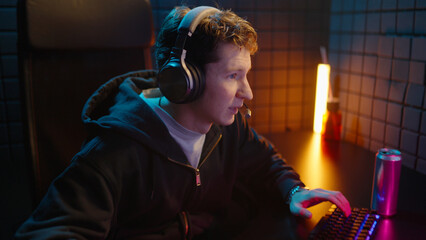 Young teen streamer gamer man playing online video game on computer. Esport concept gaming virtual entertainment. Cyber e sport videogame tournament live stream. Neon light. Tense player competition. © Татьяна Епанешникова
