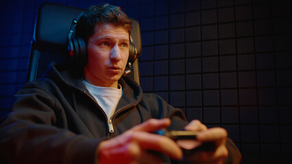 Young teen boy streamer gamer man playing online video game on computer use joystick. Gaming console virtual entertainment. Cyber e sport videogame controller. Neon light. Tense player hold joypad. © Татьяна Епанешникова