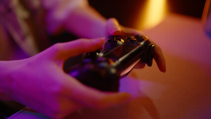 Young teen girl streamer gamer woman playing online video game on computer use joystick. Gaming console virtual entertainment. Cyber e sport videogame controller. Neon light. Tense player hold joypad. © Татьяна Епанешникова