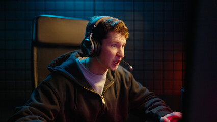 Young teen streamer gamer man playing online video game on computer. Esport concept gaming virtual entertainment. Cyber e sport videogame tournament live stream. Neon light. Tense player competition. © Татьяна Епанешникова