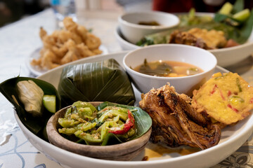 Traditional Indonesian Sundanese Nasi Liwet Set with Grilled Chicken, Sambal, Corn Fritters, and Sour Soup