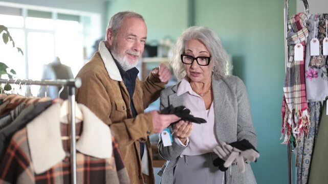 Elderly husband and wife chooses warm gloves in a clothing store. High quality 4k footage