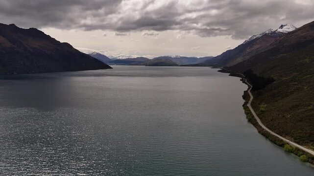 Aerial view of Lake Wakatipu and the mountains of New Zealands South island under a cloudy sky.