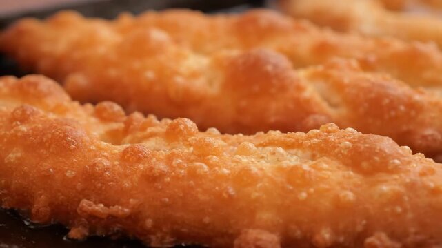 Macro shot of crispy golden deep-fried dough surface, showcasing the detailed, bubbly texture of hot street food pastry or fritter.