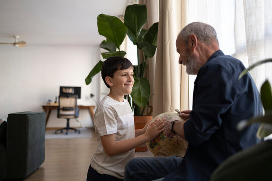 Grandfather and grandson explore globe together in living room