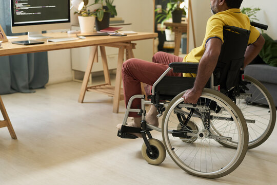 Freelancer in wheelchair working on programming script at home office