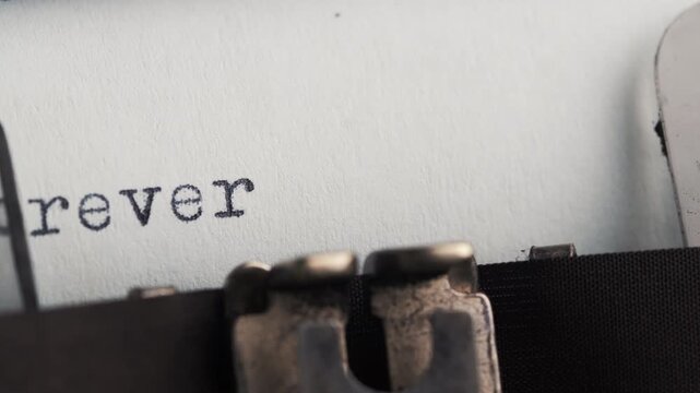 Typing the word forever yours on a sheet of paper in a vintage typewriter located in a cozy space during daylight