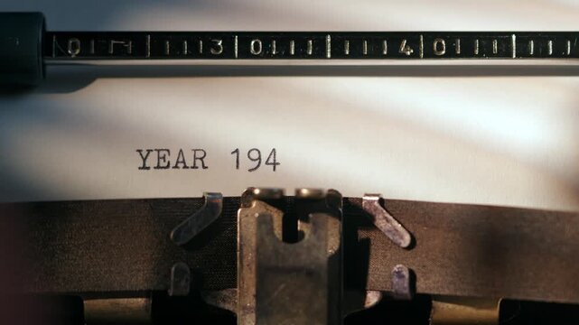 Typewriter shows the word YEAR 1945 typed on paper in an office setting with vintage equipment
