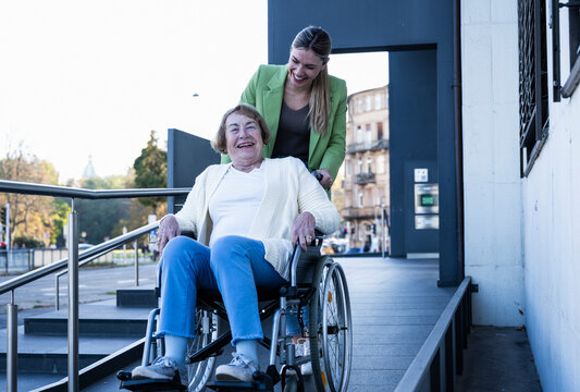 Happy granddaughter wheeling grandmother on ramp
