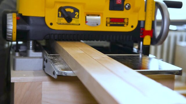 Closeup of carpenter man shaping wooden block on planer thicknesser jointer machine in workshop. Woodworking process, furniture preparation, handmade craftsmanship, precision tools, carpentry studio