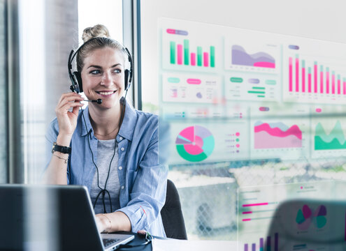 Smiling business professional with headset working on data analysis at office