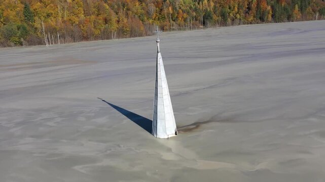 Aerial slow motion apocalyptic scene, church tower with cross buried under mud and toxic copper mining residuals. Geamana, Romania