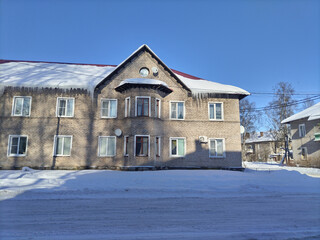 beautiful icicles on a house, a two-story house, a blue sky, winter,