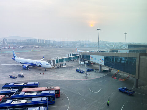Mumbai, India - October 21, 2025: Indigo Airlines aircraft parked at Mumbai International Airport with boarding bridge and ground vehicles in view during sunset