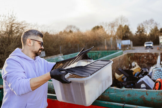Man sorting plastic container at recycling facility.
