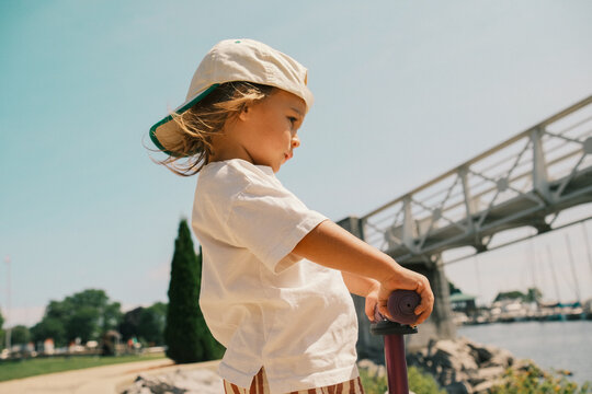 Toddler riding scooter in sunny park