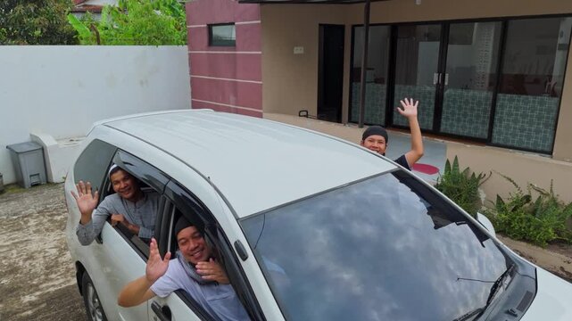 Cheerful family muslim waving goodbye from car departing for traditional Mudik holiday trip