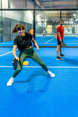 Naklejka premium Woman playing pickleball on indoor blue court