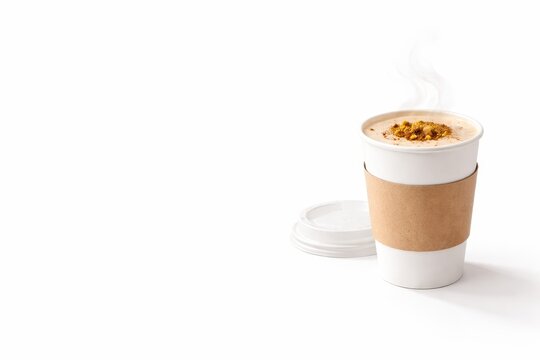 Hot salep drink in takeaway paper cup with blank kraft sleeve topped cinnamon and pistachio warm winter beverage